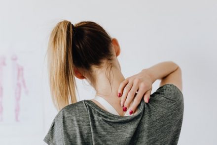 femme de dos se touchant la nuque