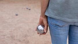 personne tenant une boule de pétanque dans sa main