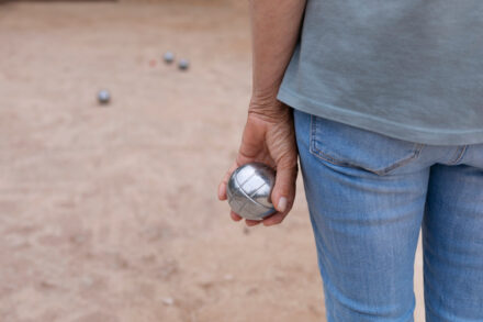 personne tenant une boule de pétanque dans sa main