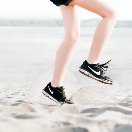 jambes de femme en baskets courant sur le sable