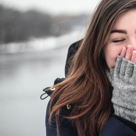 femme se mettant la main vêtus d'une mitaine sur le nez et le visage