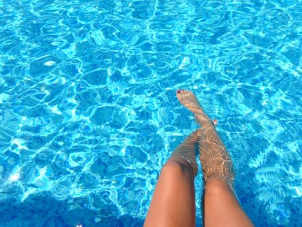 jambes de femme trempant dans l'eau bleue d'une piscine