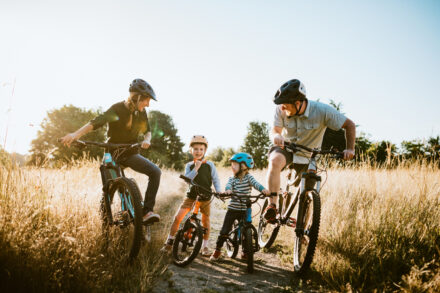 Des parents et leurs enfants font du vélo dans les champs en pleine campagne