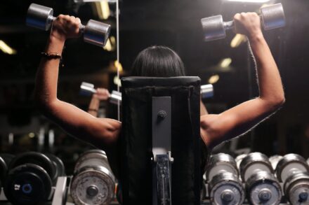 femme sur un banc de musculation en train de faire des développés aux haltères