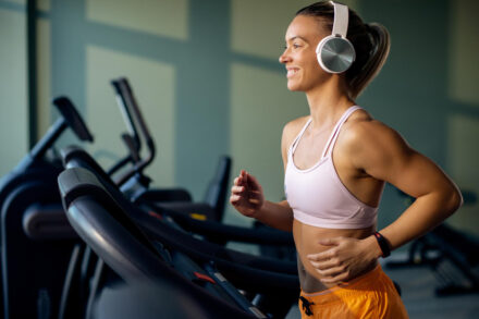 femme sportive faisant du tapis de course casque sur les oreilles