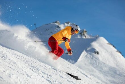 skieur en jaune et rouge dévalant une piste