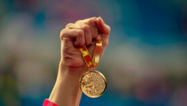 photo de JO avec une main tenant une médaille d'or olympique