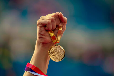 photo de JO avec une main tenant une médaille d'or olympique