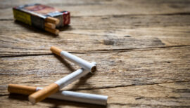3 cigarettes et un paquet de cigarettes posés sur une table