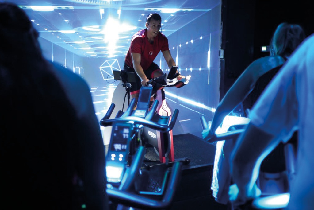 Coach donnant un cours de cycling dans un studio avec des lumières bleues à aix en provence