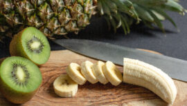 banane coupée en rondelles et kiwi coupé en deux avec un ananas en arrière plan