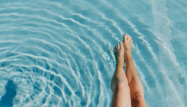jambes de femme les pieds dans l'eau d'une piscine
