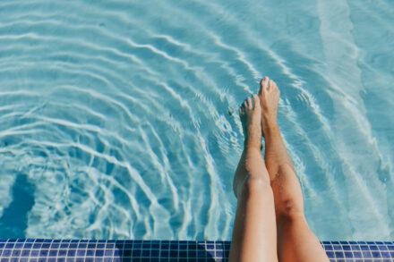 jambes de femme les pieds dans l'eau d'une piscine