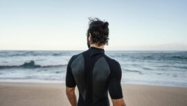 homme en shorty en bord de mer avant sa session de longe côte