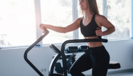 femme en salle de sport faisant du vélo elliptique